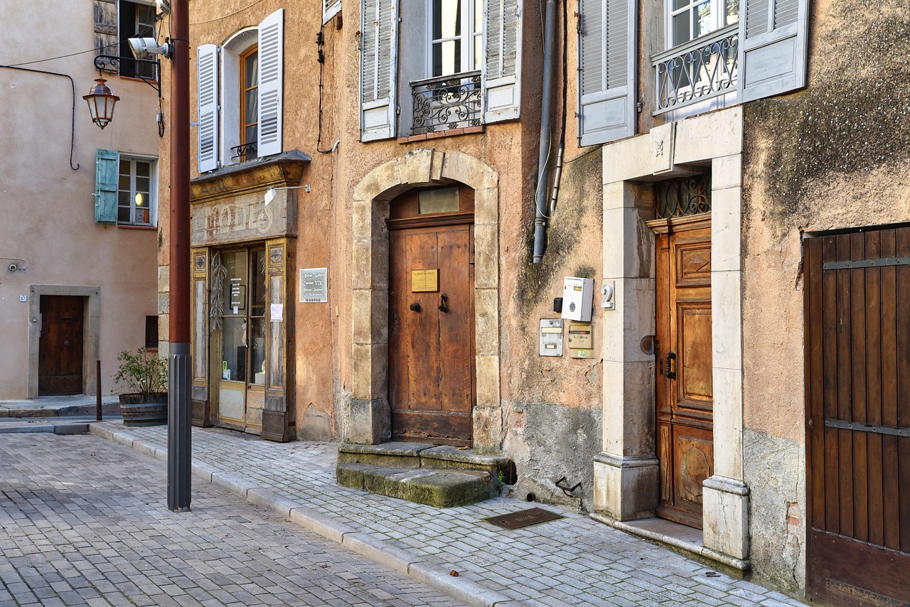 Ancienne devanture de boutique de modes et portes en bois dans une rue pavée de village