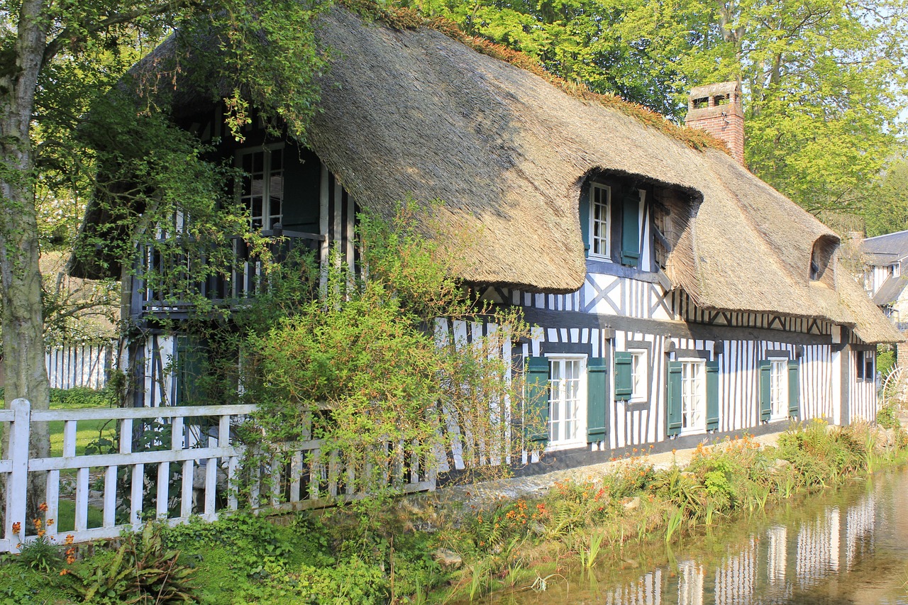 Chaumière normande à colombages et volets verts au bord d'une rivière