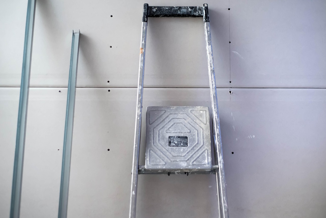 Escabeau contre une cloison en plaques de plâtre neuve, rails métalliques posés à côté