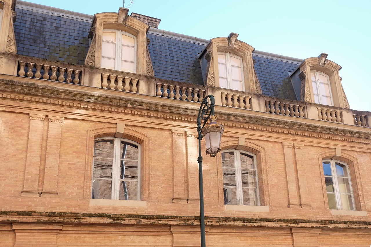 façade d'immeuble ancien en brique rose, lucarnes en pierre, balustrade et toit d'ardoise