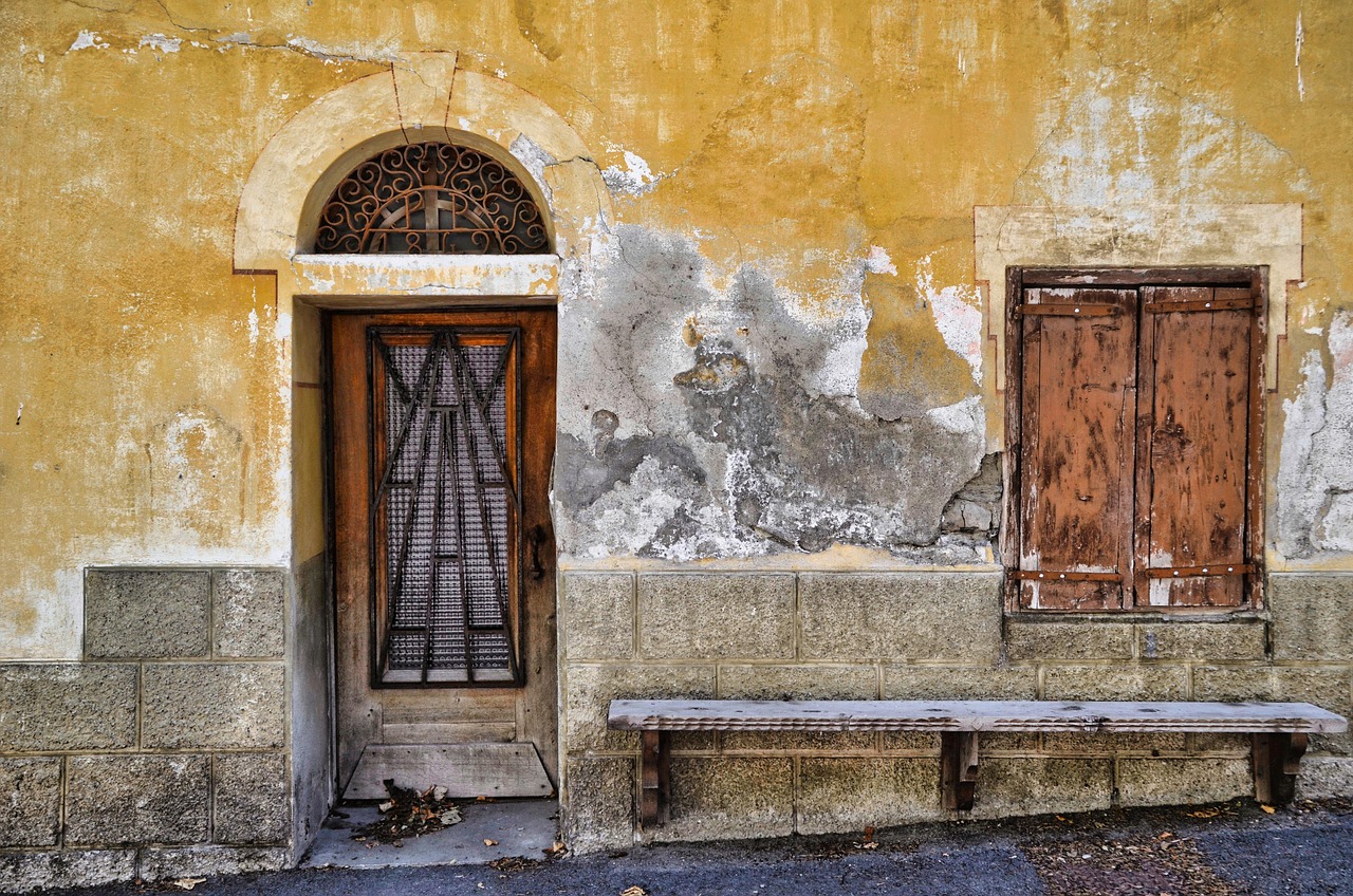 Façade ancienne à l’enduit écaillé, porte et volets usés