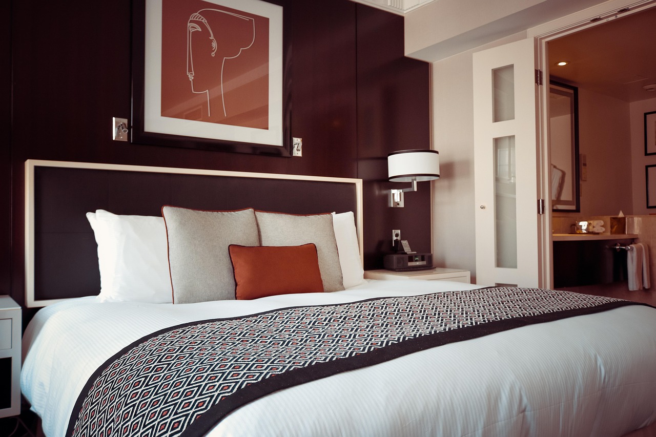 Chambre d'hôtel avec grand lit, tête de lit sombre et salle de bains attenante