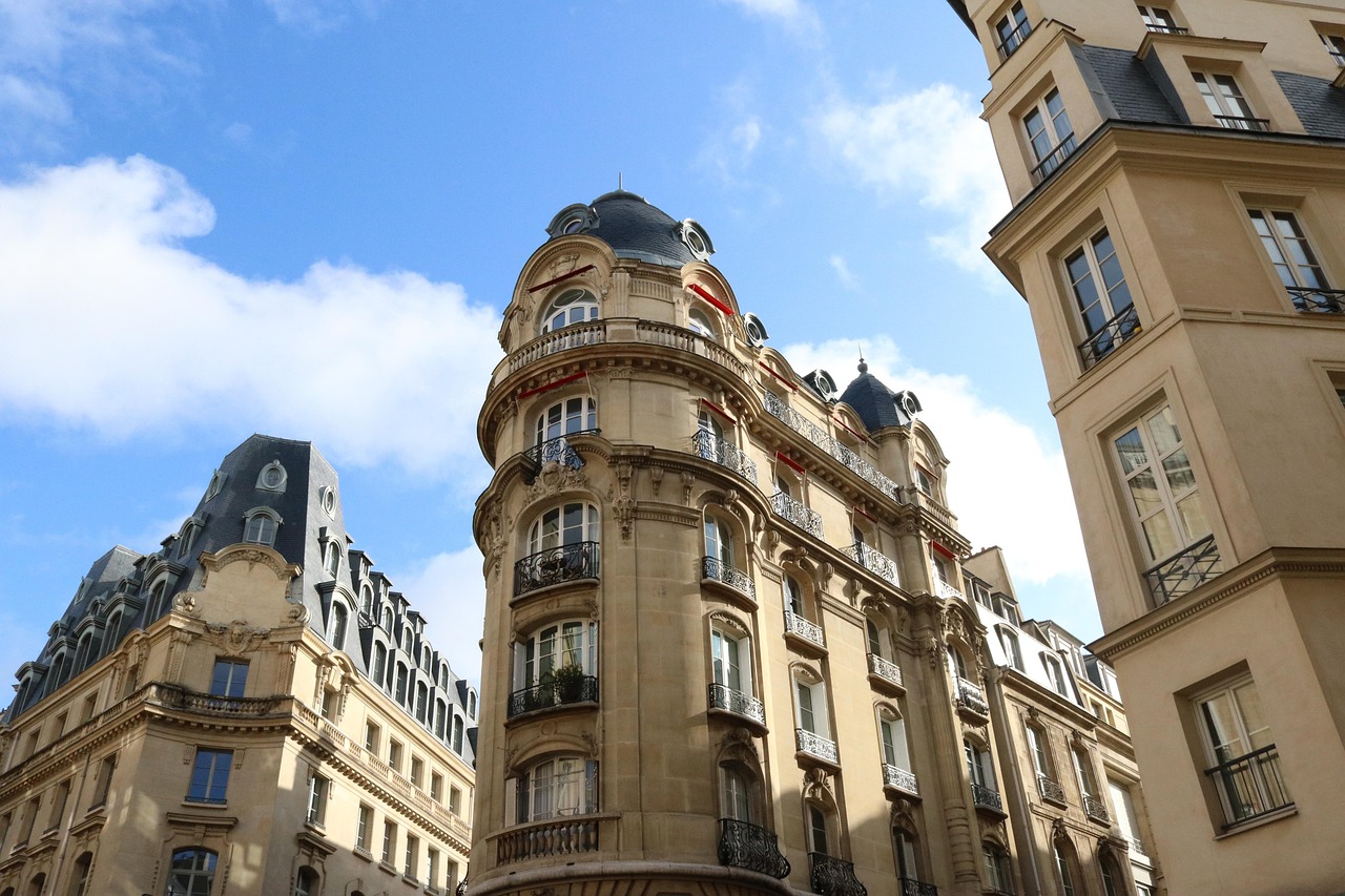 Immeuble haussmannien d'angle à rotonde coiffée d'un dôme d'ardoise, balcons en fer forgé, sous un ciel bleu