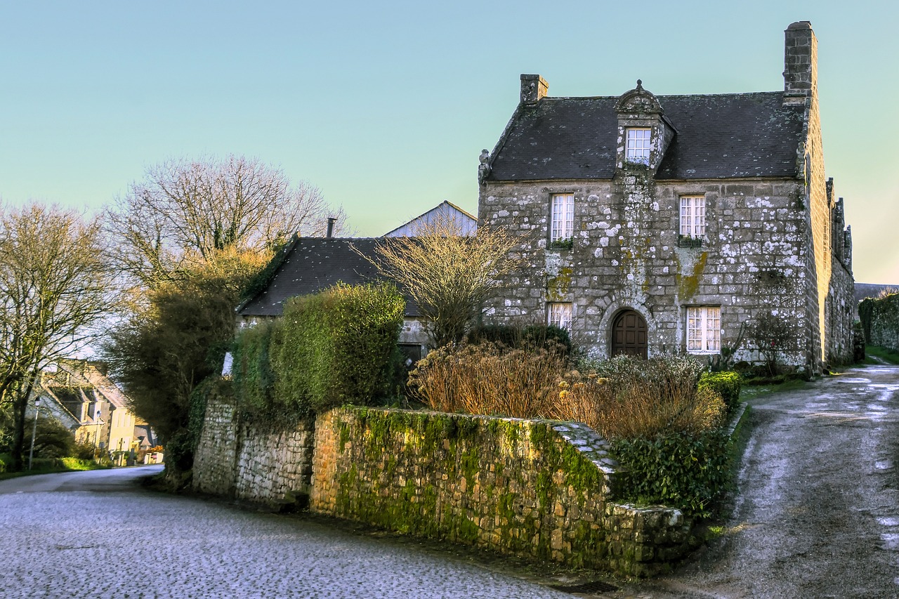 Maison ancienne en pierre et muret moussu au bord d'une route givrée