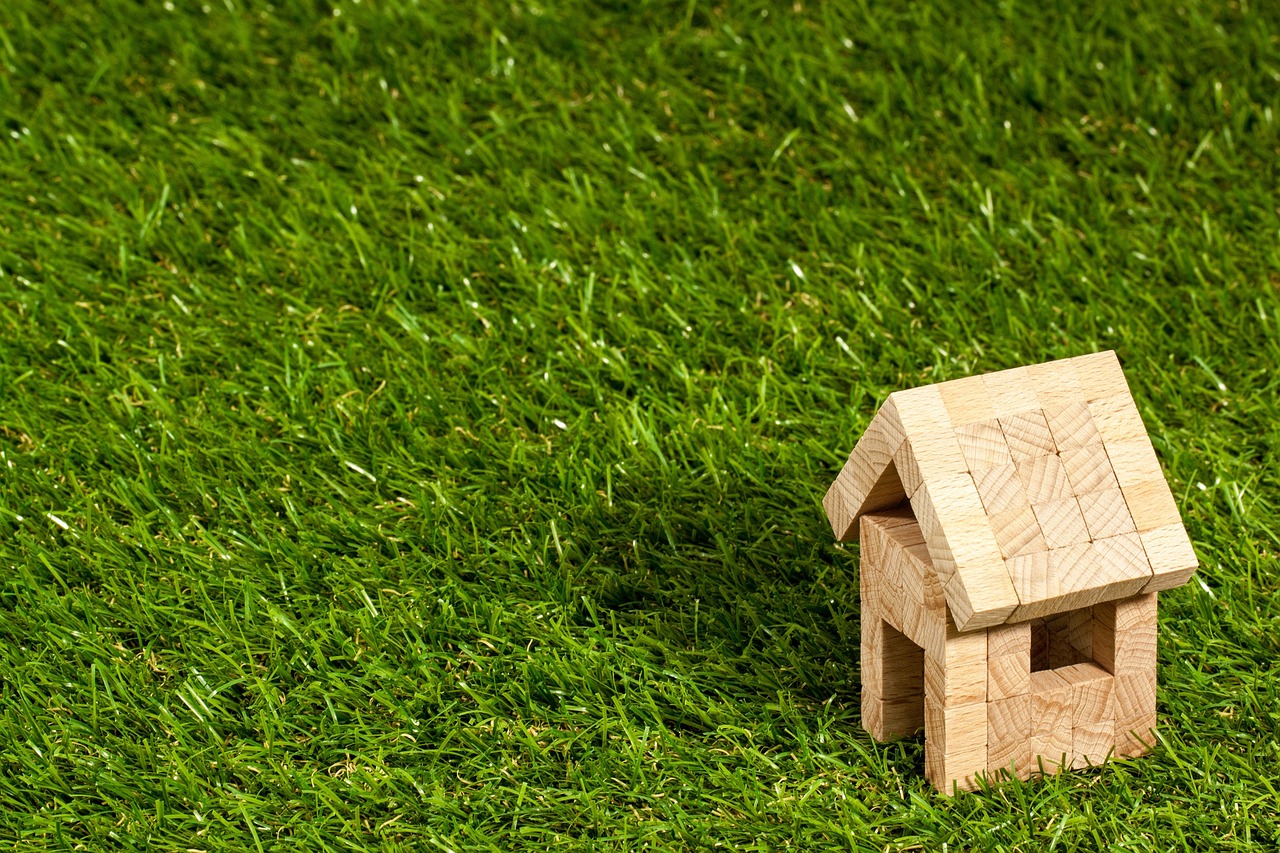 Miniature house built from wooden blocks on a lawn