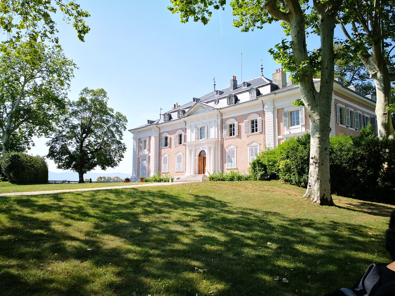 Maison de maître devant une pelouse et de grands arbres
