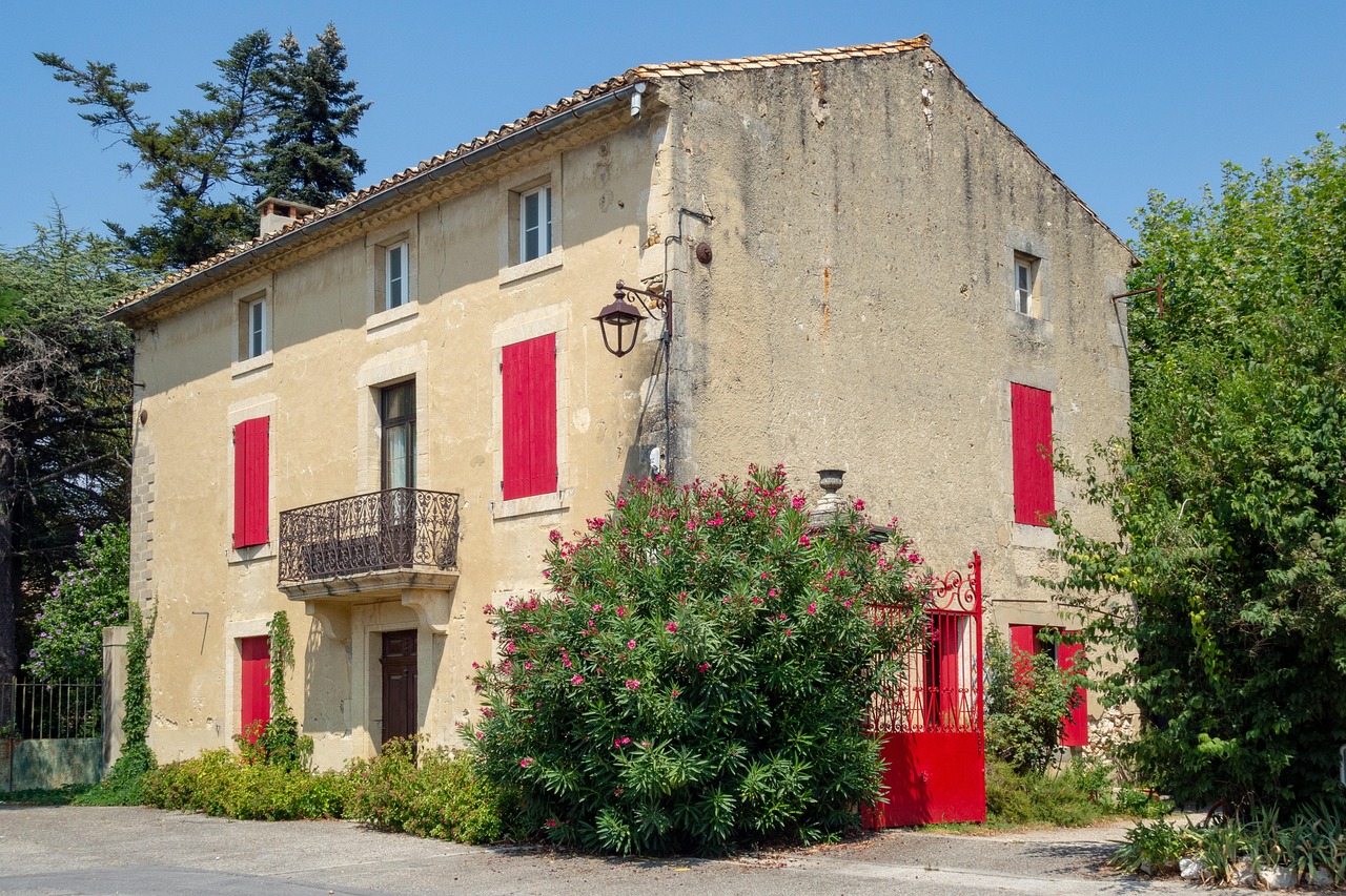 stone townhouse with red shutters, a wrought-iron balcony and an oleander, in the south of France