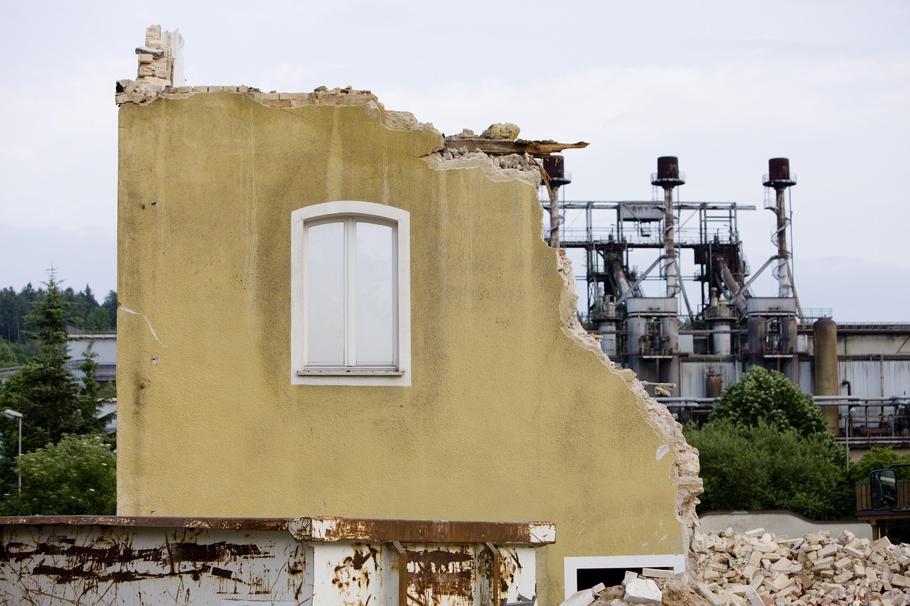 House being demolished in front of an industrial site