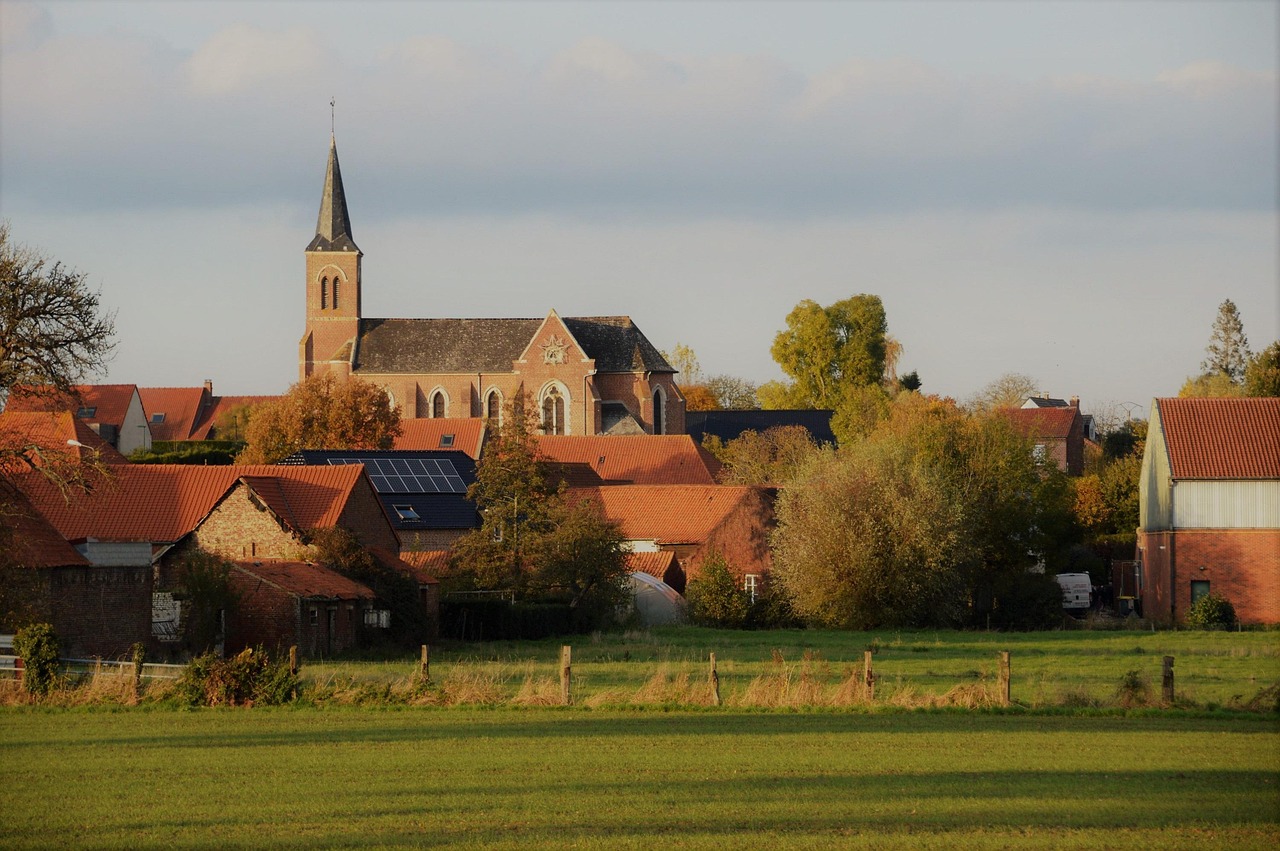 prairie non bâtie et clôturée en lisière d'un village de briques dominé par son église
