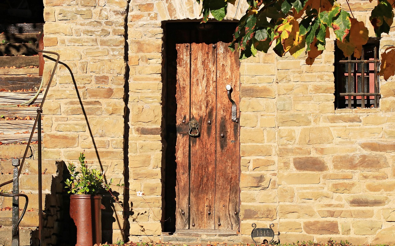 Porte en bois d’une maison en pierre avec une plante en pot