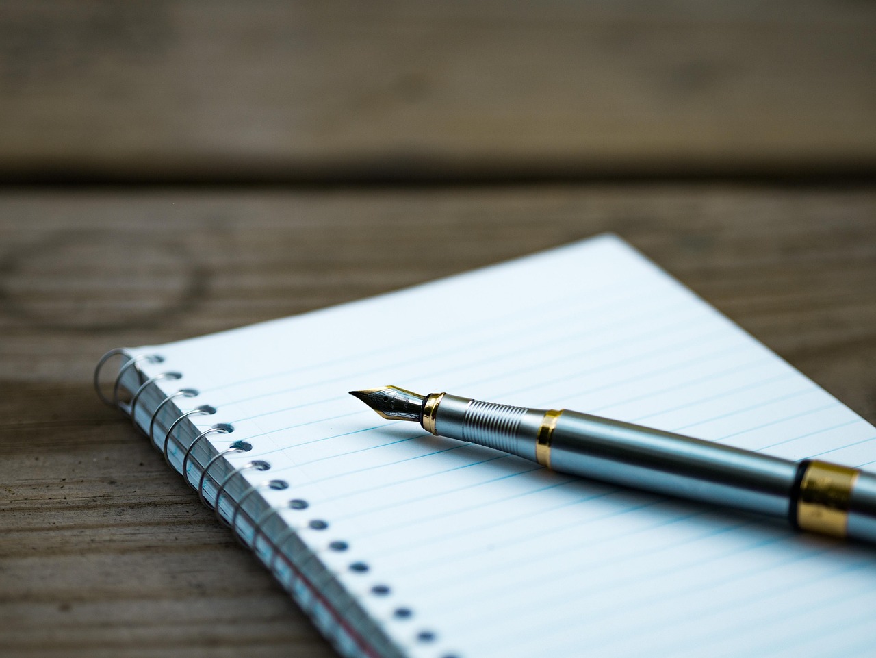Fountain pen resting on a blank spiral notebook